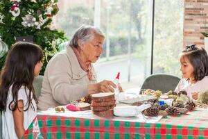 Grandmother teaching her granddaughters how to make christmas Nativity crafts - Real family photo