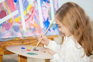 Little blonde girl painting outdoors photo
