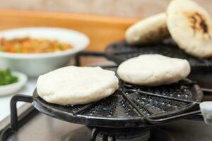 Colombiana arepas siendo asado en un redondo parrilla foto