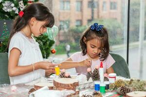 Two little sisters having fun while making christmas Nativity crafts with at home - Real family photo