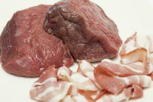 Raw medallions of beef tenderloin and pork bacon. Filet mignon preparation. photo