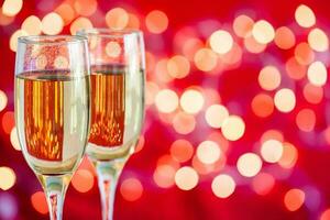 Champagne glasses on light bokeh red background photo