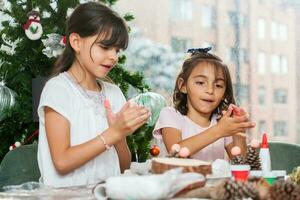 Two little sisters having fun while making christmas Nativity crafts with at home - Real family photo