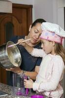 madre y hija teniendo divertido en el cocina horneando juntos. preparando magdalenas con mamá foto