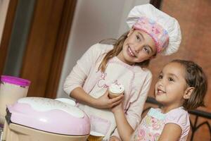 Sisters having fun baking cupcakes together at home. photo