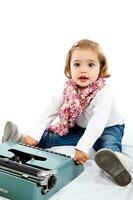 Beautiful little blonde girl playing with a typewriter photo