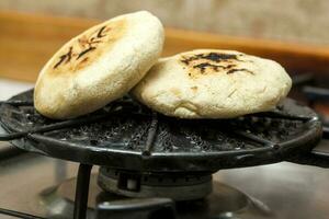 relleno Colombiana arepa preparación. Colombiana arepas siendo asado en un redondo parrilla foto