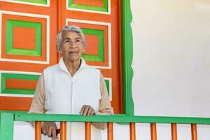 Senior woman at a traditional colorful balcony in the beautiful colonial town of Salento in the region of Quindio in Colombia photo