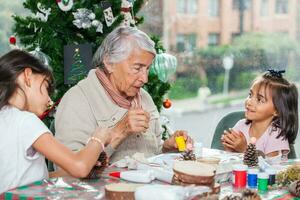 Grandmother teaching her granddaughters how to make christmas Nativity crafts - Real family photo