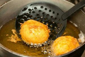 Preparation steps of traditional Colombian dish called stuffed potatoes. Deep frying stuffed pototoes photo