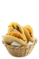 Arepa de huevo. Traditional Colombian fried arepa filled with egg and shredded meat on white background photo