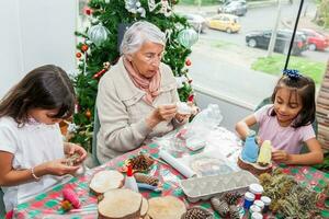 abuela enseñando su nietas cómo a hacer Navidad natividad artesanía - real familia foto