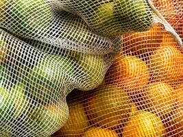 Close up of bags filled with oranges and lemons photo