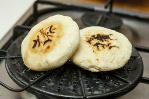 Stuffed Colombian arepa preparation. Colombian arepas being roasted on a round grill photo