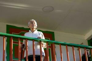 Senior woman at a traditional colorful balcony in the beautiful colonial town of Salento in the region of Quindio in Colombia photo