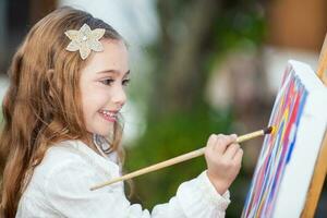 Little blonde girl painting outdoors photo