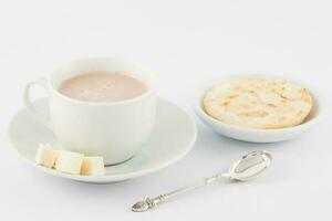 Cup of hot chocolate with cheese and arepa served in white dishware photo