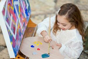 Little blonde girl painting outdoors photo