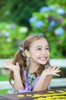 hermosa pequeño niña jugando al aire libre con un rompecabezas. mirando para soluciones foto