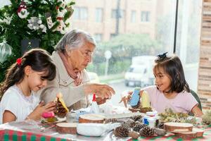 Grandmother teaching her granddaughters how to make christmas Nativity crafts - Real family photo