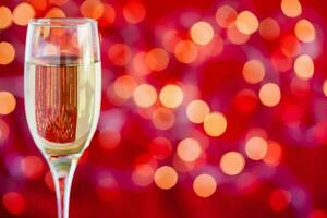 Champagne glass on light bokeh red background photo