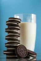 Stack of chocolate cookies and milk on blue background photo