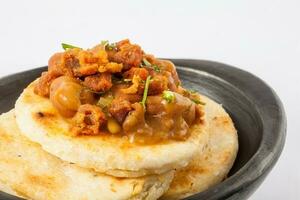 Traditional Colombian arepa topped with beans and pork rind photo