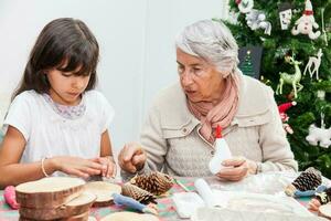 Grandmother teaching her granddaughter how to make christmas Nativity crafts - Real family photo