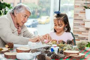 Little girl having fun while making christmas Nativity crafts with her grandmother - Real family photo