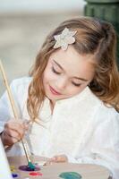 Little blonde girl painting outdoors photo