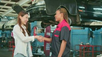 Young Asian female customer handshakes with car mechanical worker with happy smiles, trust, and impressive at maintenance garage, professional vehicle service center, fix checks, and repair industry. video