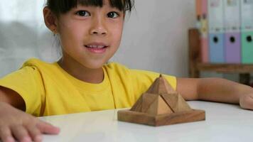 asiatico carino poco ragazza giocando con di legno giocattolo sega puzzle piramide su tavolo. salutare bambini formazione memoria e pensiero. di legno puzzle siamo Giochi quello aumentare intelligenza per bambini. video