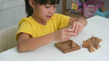 ásia fofa pequeno menina jogando com de madeira brinquedo quebra-cabeças enigma pirâmide em mesa. saudável crianças Treinamento memória e pensamento. de madeira quebra-cabeças estão jogos este aumentar inteligência para crianças. video