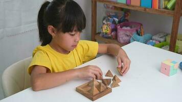 asiático linda pequeño niña jugando con de madera juguete rompecabezas rompecabezas pirámide en mesa. sano niños formación memoria y pensamiento. de madera rompecabezas son juegos ese incrementar inteligencia para niños. video