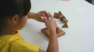 asiatico carino poco ragazza giocando con di legno giocattolo sega puzzle piramide su tavolo. salutare bambini formazione memoria e pensiero. di legno puzzle siamo Giochi quello aumentare intelligenza per bambini. video