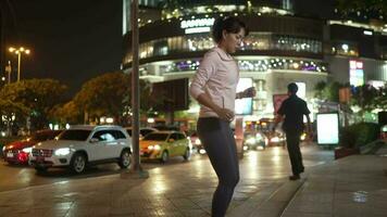 fêmea atleta dentro encapuzado camisa pulando às noite cidade ruas com grande quantidade do luzes dentro a fundo. video