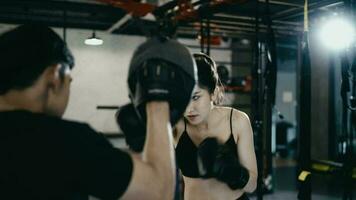 boxe treinador Treinamento em forma branco fêmea boxer às Academia dentro lento movimento. barbudo instrutor dentro luvas trabalhando com menina atleta. bem-estar, concorrência, combate, motivação conceito video