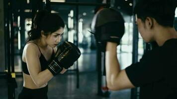 boxing coach training fit white female boxer at gym in slow motion. bearded instructor in mitts working with girl athlete. Wellness, competition, combat, motivation concept video