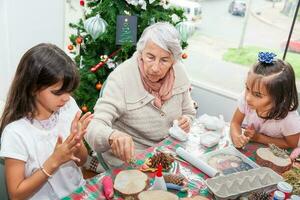 abuela enseñando su nietas cómo a hacer Navidad natividad artesanía - real familia foto