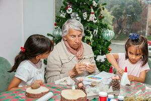 Little girls having fun while making christmas Nativity crafts with their grandmother - Real family photo
