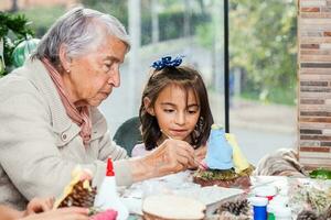 Grandmother teaching her granddaughter how to make christmas Nativity crafts - Real family photo