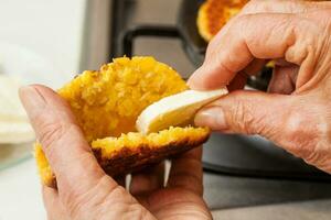 Traditional Colombian Arepa de Choclo Preparation. Stuffing the cooked corn bread with cheese photo