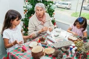 abuela enseñando su nietas cómo a hacer Navidad natividad artesanía - real familia foto