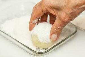 Preparation steps of traditional Colombian dish called stuffed potatoes. Covering the stuffed potatoes with flour photo