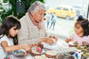 Grandmother teaching her granddaughters how to make christmas Nativity crafts - Real family photo