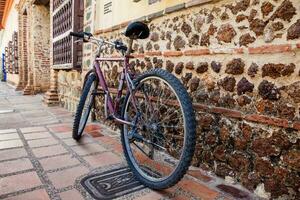 Bicycle parked next to an ancient stone wall at the colonial town of Santa Fe de Antioquia in Colombia photo