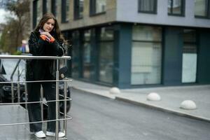 Young girl in leather jacket posed in urban city, holding credit card with handbag and phone. photo