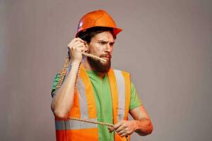 Man in construction uniform orange hard hat cropped view over beige background photo