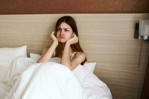 upset woman woke up early in the morning in bed under a white blanket photo