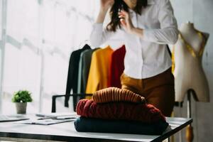 Beautiful lady blogger showing clothes in front of the camera to recording vlog video live streaming at her shop. Online Shopping Cart notion. photo